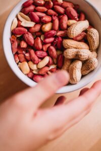 Close-up of fresh peanuts in a bowl with a hand reaching in. Nutritious snack.