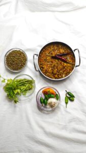 Top view of Indian lentil dish with spices and herbs, ideal for culinary themes.