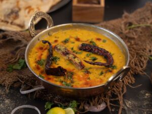 Delicious Indian lentil curry garnished with dried chilies and cilantro in an ornate bowl.