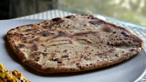 Delicious close-up of a traditional Indian paratha served on a white plate, perfect for culinary themes.