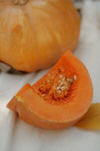 Vertical shot of a sliced pumpkin on fabric, highlighting its seeds and rich texture.