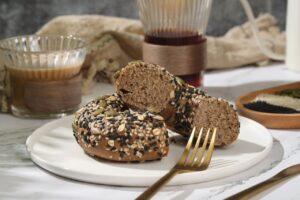 Delicious seeded bagel on plate with coffee, perfect for a hearty breakfast.